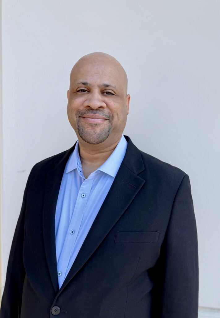 mike-roberts-headshot-2 copy Mike Roberts smiling at the camera with a suit on.