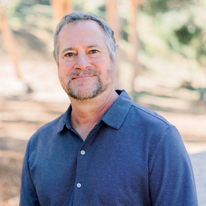 Mike Roberts, Founder and CEO of Creating Coding Careers, smiling in a casual black polo shirt against a neutral background, embodying leadership and commitment to diversity in tech.